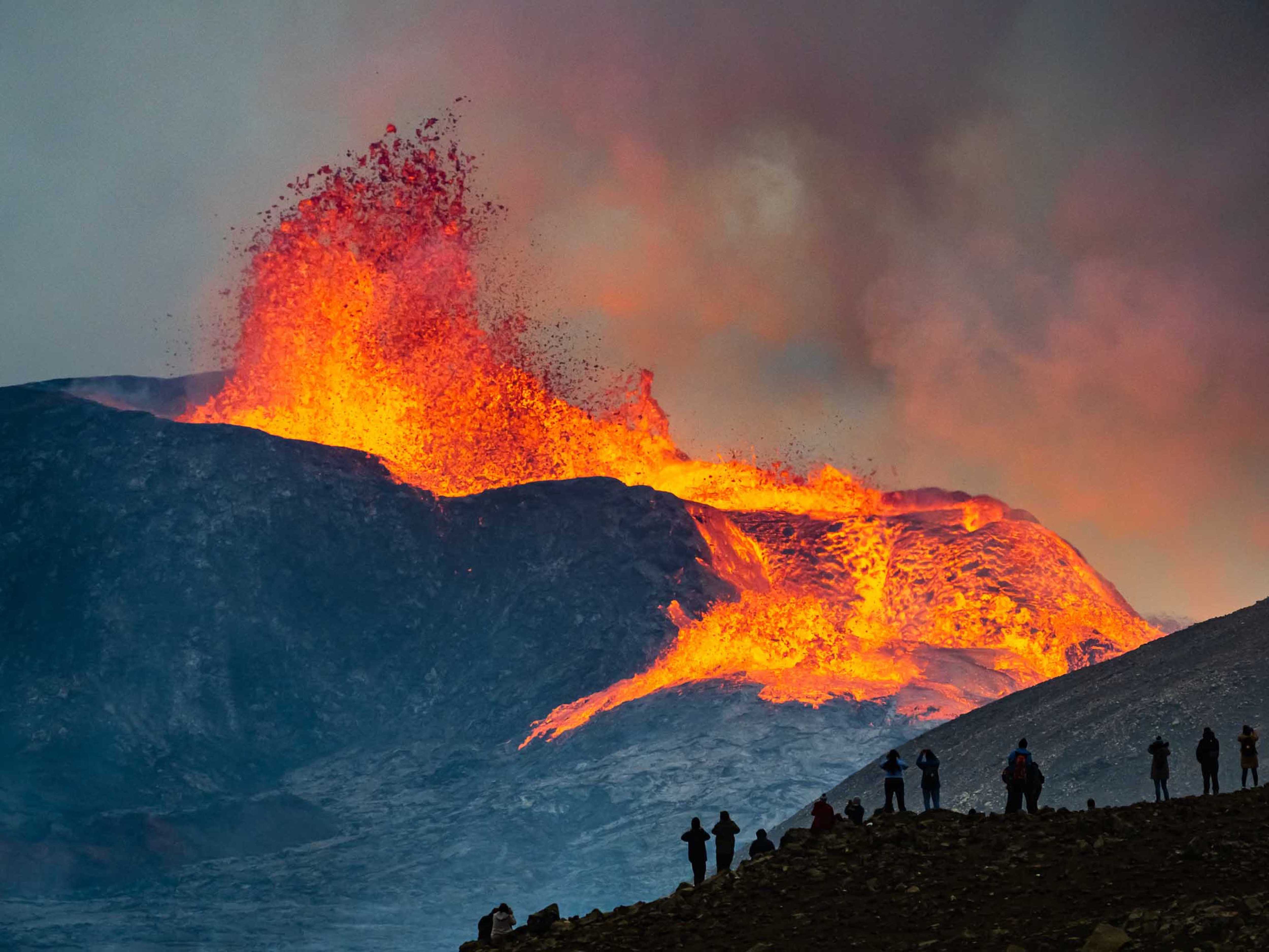 Silhouettes of onlookers watching the Iceland volcano erupt
