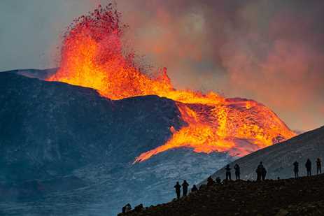 Silhouettes of onlookers watching the Iceland volcano erupt